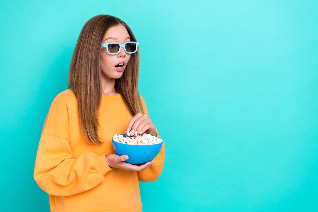 Fotografie mladé dívky dospívající věk držet popcorn jíst občerstvení nevyžádané jídlo oblečení 3d brýle šokovaný vzhled mockup trailer nový film izolované na cyan barevné pozadí. - Fotografie, Obrázek