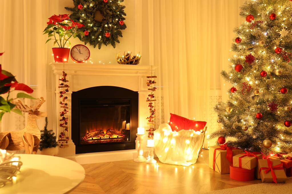Beautiful living room interior with burning fireplace and Christmas tree in evening - Zdjęcie, obraz