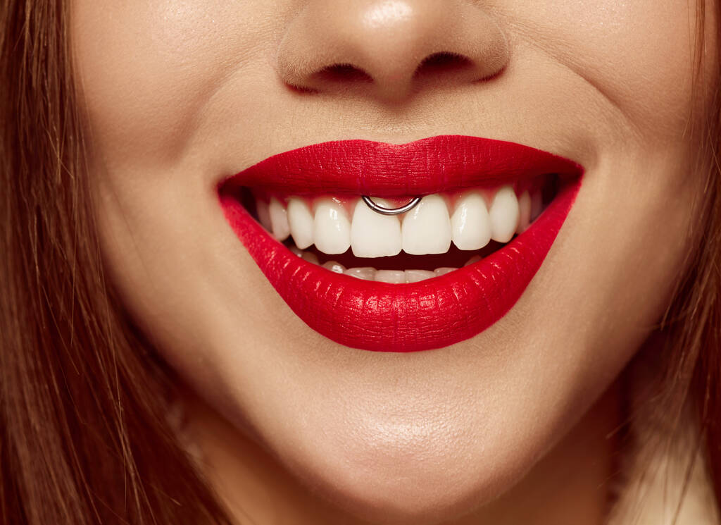 Nahaufnahme des weiblichen Mundes mit knallrotem Lippenstift. Schönes breites Lächeln einer jungen Frau mit großen gesunden weißen Zähnen und gepflegter Haut. Gesundheit, Schönheit, Wellness, Kunst und Werbekonzept - Foto, Bild