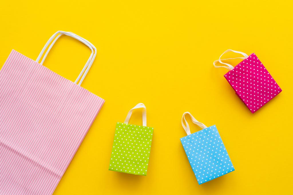 Vista superior de coloridas bolsas de compras sobre fondo amarillo  - Foto, imagen