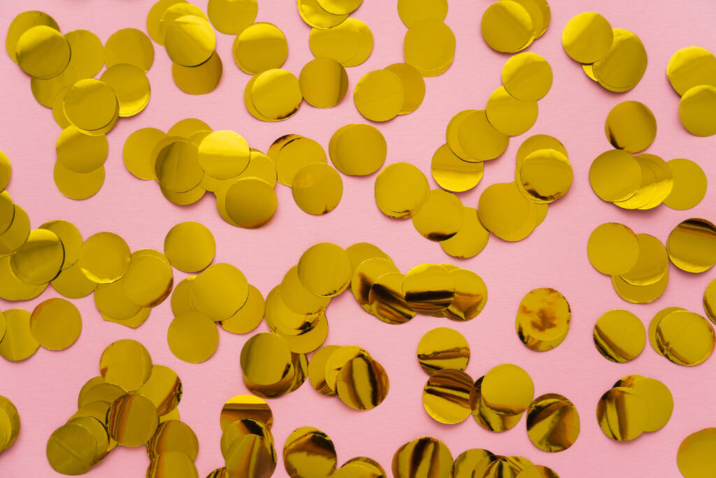 Vista superior de confeti dorado sobre fondo rosa  - Foto, imagen