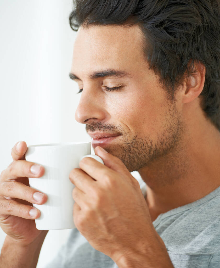 Ízlelgeti a reggeli kávéját. egy jóképű fiatalember, aki egy csésze kávét iszik. - Fotó, kép