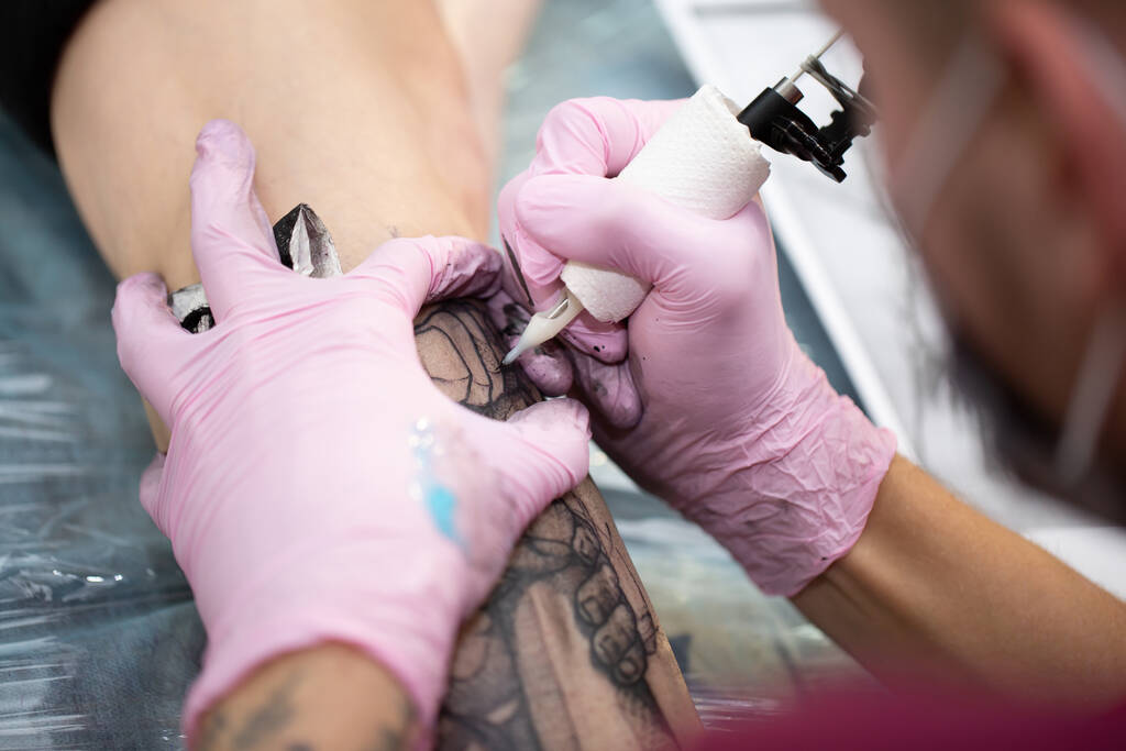 The tattoo master draws white paint on the clients  tattoos - Photo, Image