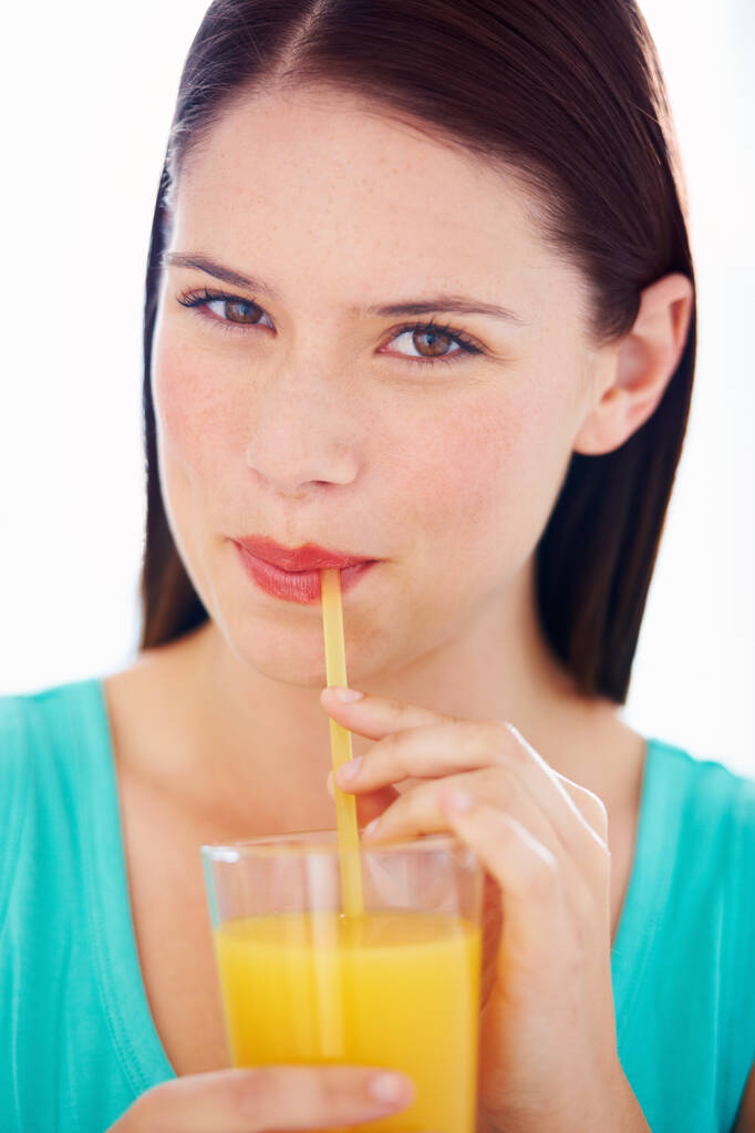 Starting the day with a fresh glass of orange juice. Portrait of an attractive young woman sipping orange juice through a straw - Photo, Image