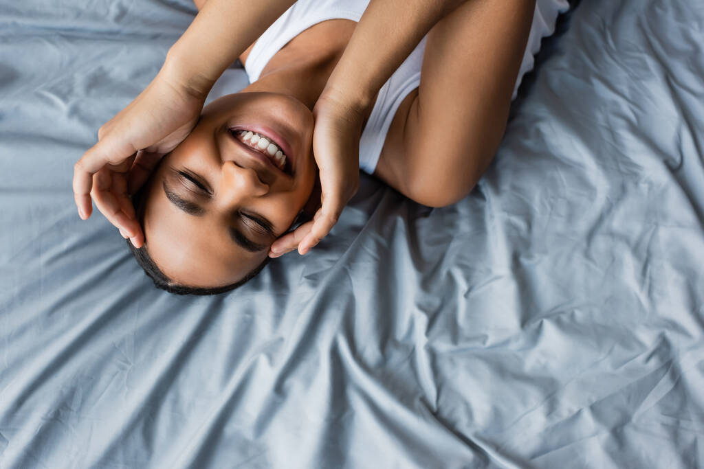 felső kilátás vidám afro-amerikai nő fekszik az ágyon otthon - Fotó, kép
