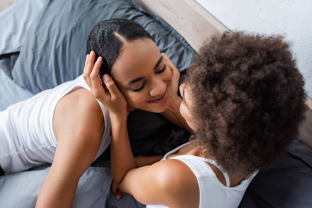 Afro-Amerikan lezbiyen kadının yatak odasında mutlu sevgiliye bakışının en üst görüntüsü.  - Fotoğraf, Görsel