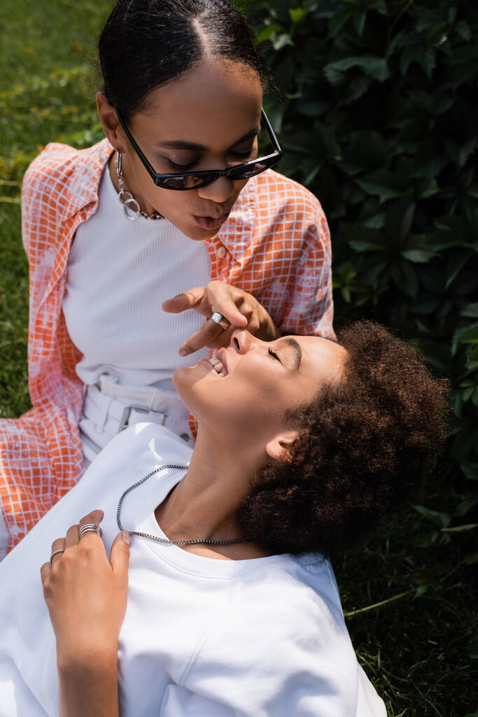 africký americký lesbička žena v sluneční brýle dotýkat nos šťastný přítelkyně v zeleném parku - Fotografie, Obrázek