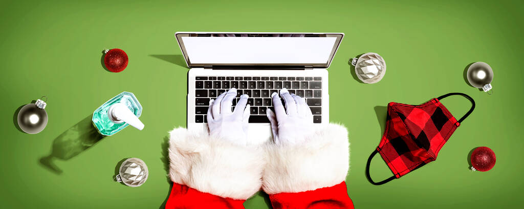 Der Weihnachtsmann mit einem Laptop mit Maske und einer Desinfektionsflasche von oben - Foto, Bild