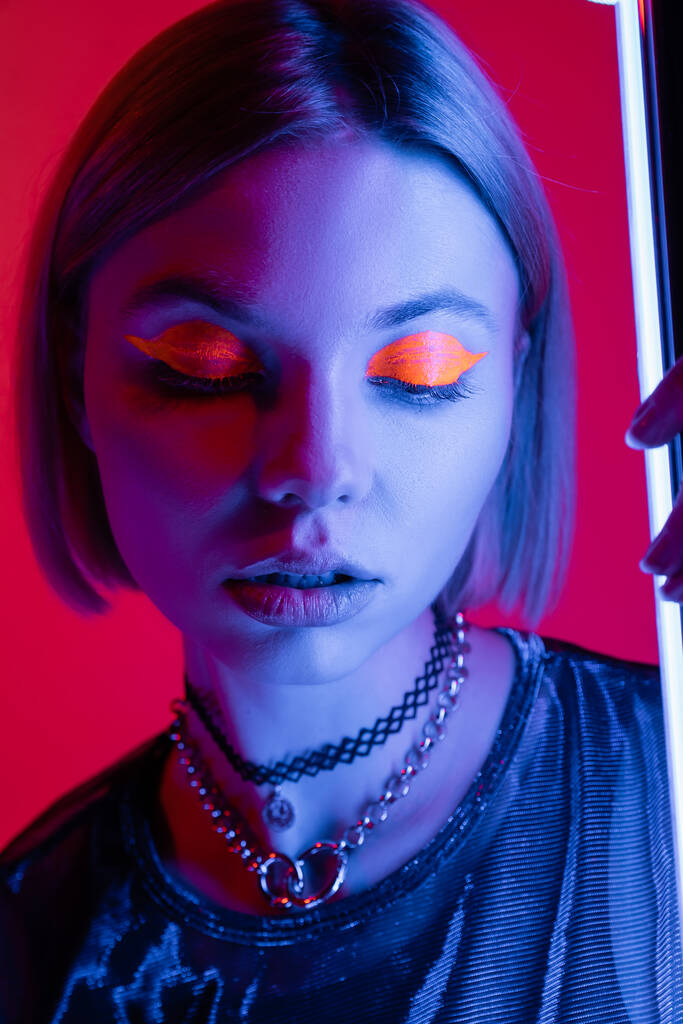 muotokuva naisen neon meikki sinisessä valossa hehkuva lamppu karmiininpunainen tausta - Valokuva, kuva