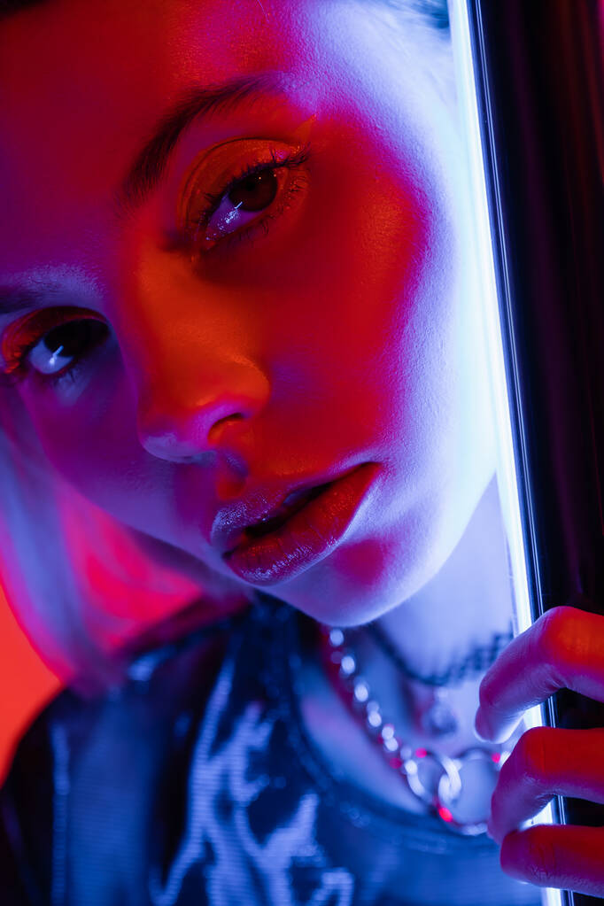 close-up portret van jonge en mooie vrouw met make-up in de buurt van lichtgevende neon lamp  - Foto, afbeelding