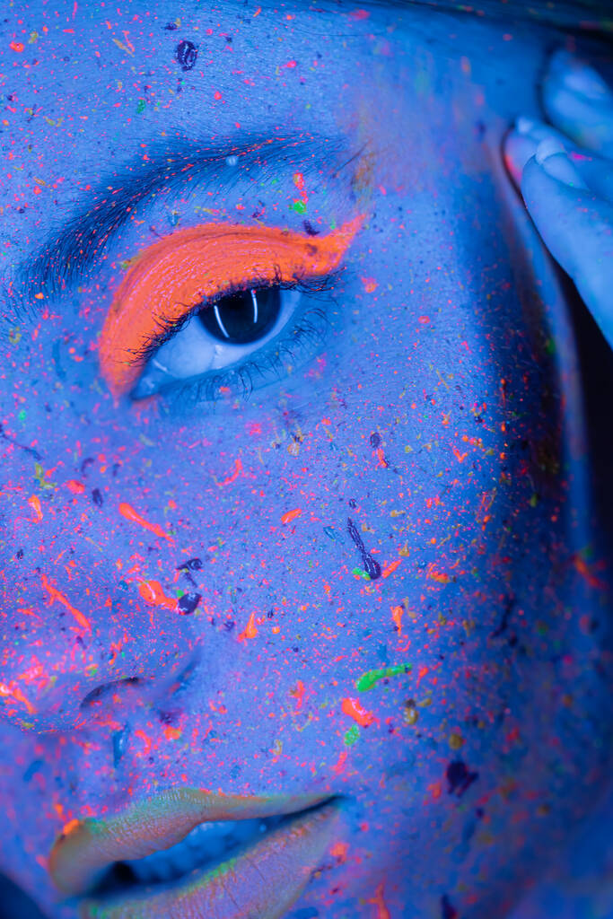 close up view of cropped woman with vibrant coral eye shadow and neon paint on face - Photo, Image