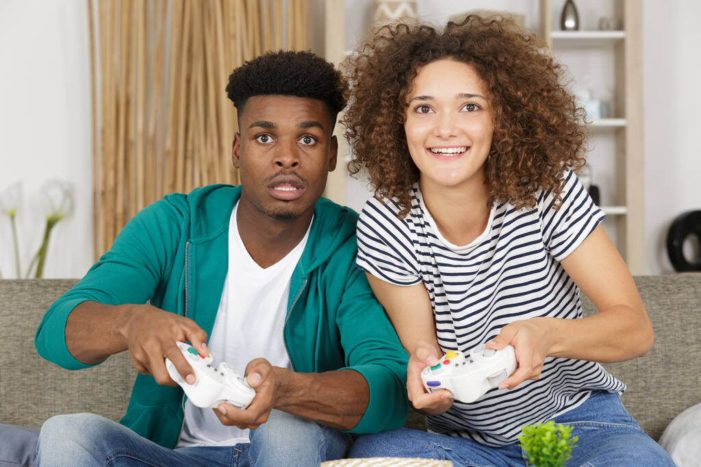 Молодая игривая пара играет в видеоигры в своей гостиной
 - Фото, изображение