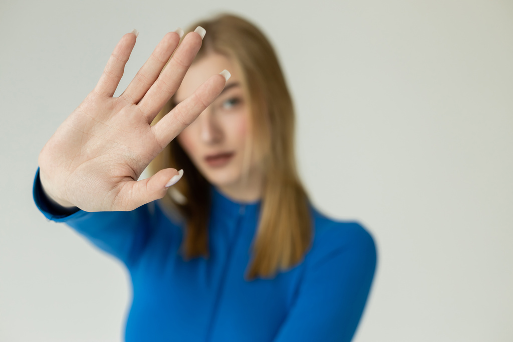 Blondine zeigt Stoppschild mit ausgestreckter Hand - Foto, Bild