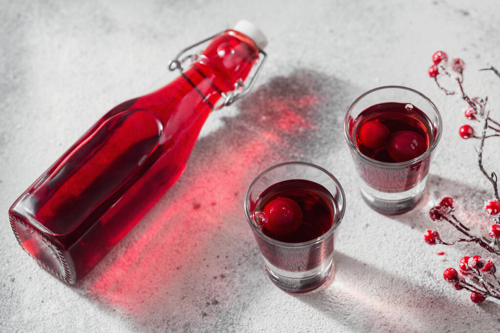 Hausgemachter Wodka, Tinktur oder Likör aus roter Kirsche auf weißem Hintergrund. Konzept für alkoholische Getränke. - Foto, Bild