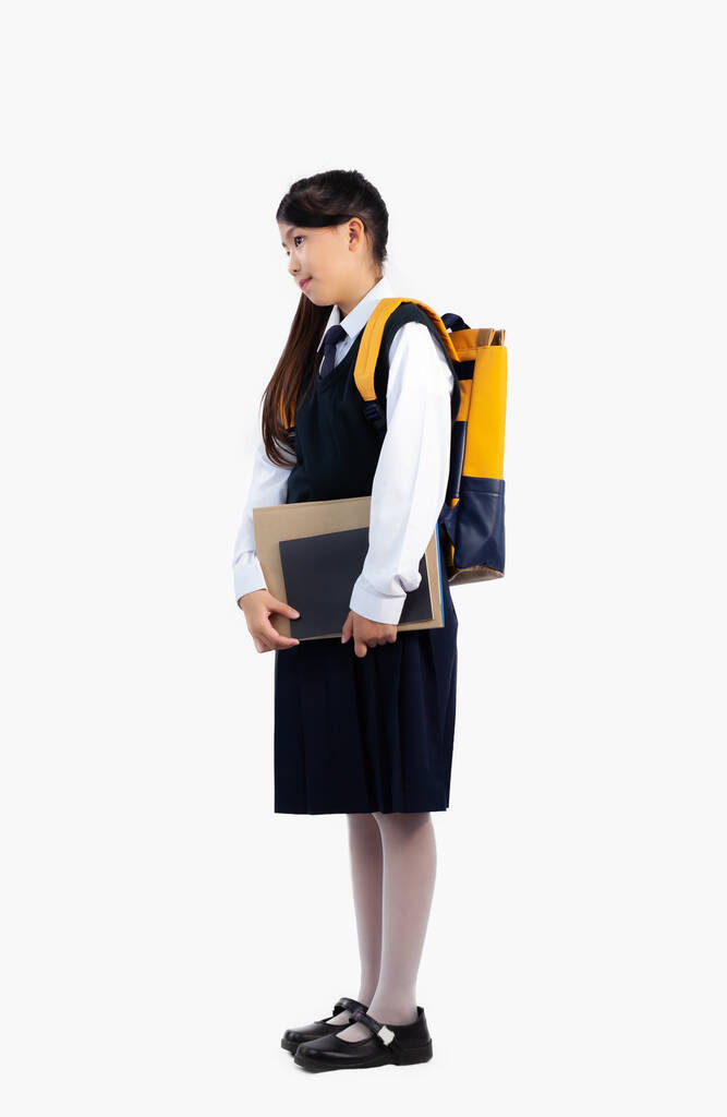 Aziatisch kind schoolmeisje in internationale school uniform staande volledige lengte dragen rugzak en boeken witte achtergrond - Foto, afbeelding