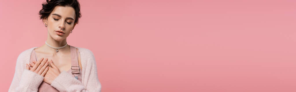 jovem sensual mulher com olhos fechados de mãos dadas no peito isolado em rosa, banner - Foto, Imagem