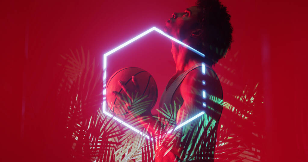 Zijaanzicht van biracial basketbalspeler met bal door zeshoek en planten op rode achtergrond. Kopieerruimte, rood, composiet, sport, competitie, illustratie, verlicht, natuur, vorm, abstract concept. - Foto, afbeelding
