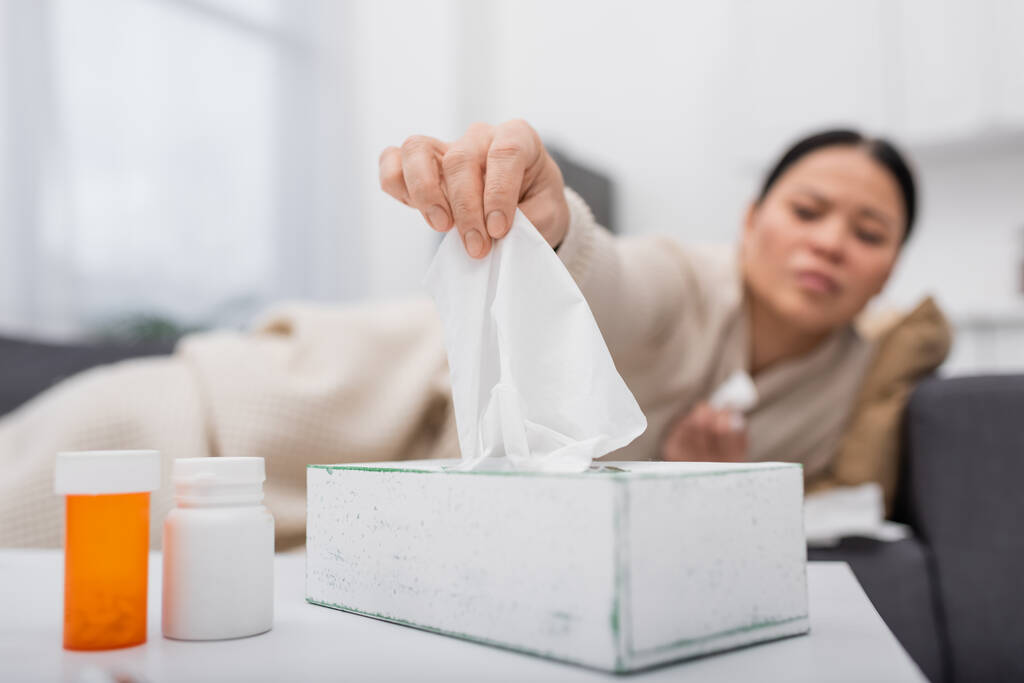 Blurred sick woman taking napkin near pills at home  - Photo, Image