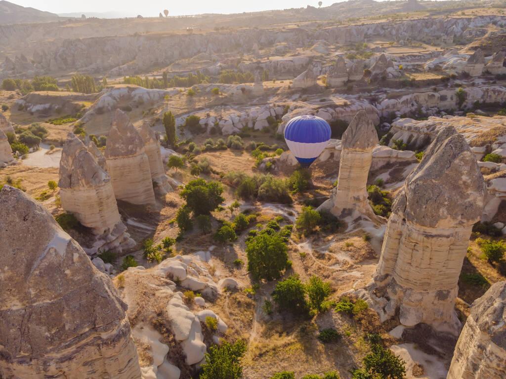 カラフルな熱気球は、ネブシェヒル、ゴーレム、カッパドキアトルコの妖精の煙突の谷で飛んでいます。地下都市と気球観光の壮大なパノラマドローンビュー。高品質. - 写真・画像
