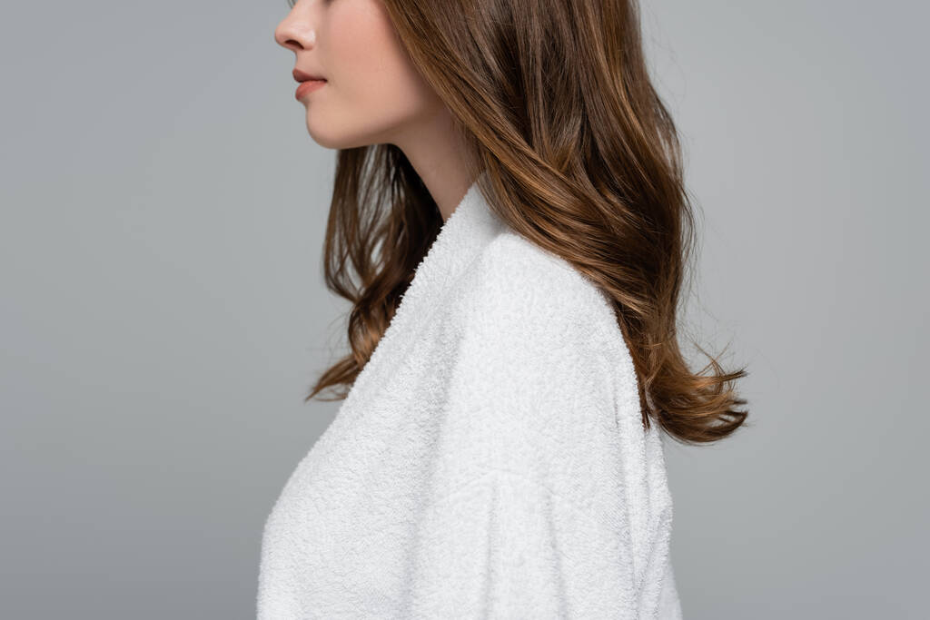 vista lateral da jovem cortada com cabelo brilhante e saudável isolado em cinza - Foto, Imagem