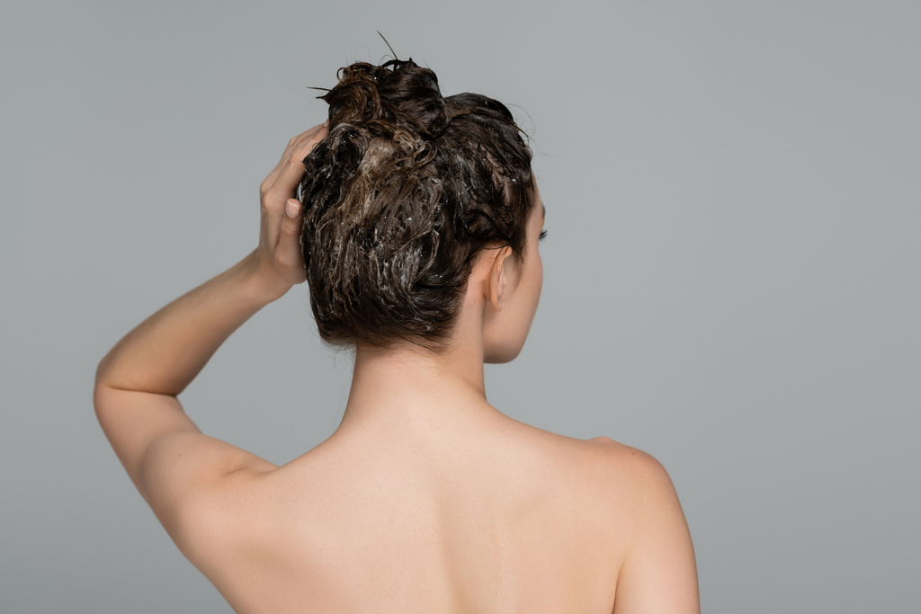 πίσω όψη της γυναίκας με γυμνούς ώμους πλύσιμο των μαλλιών απομονώνονται σε γκρι  - Φωτογραφία, εικόνα