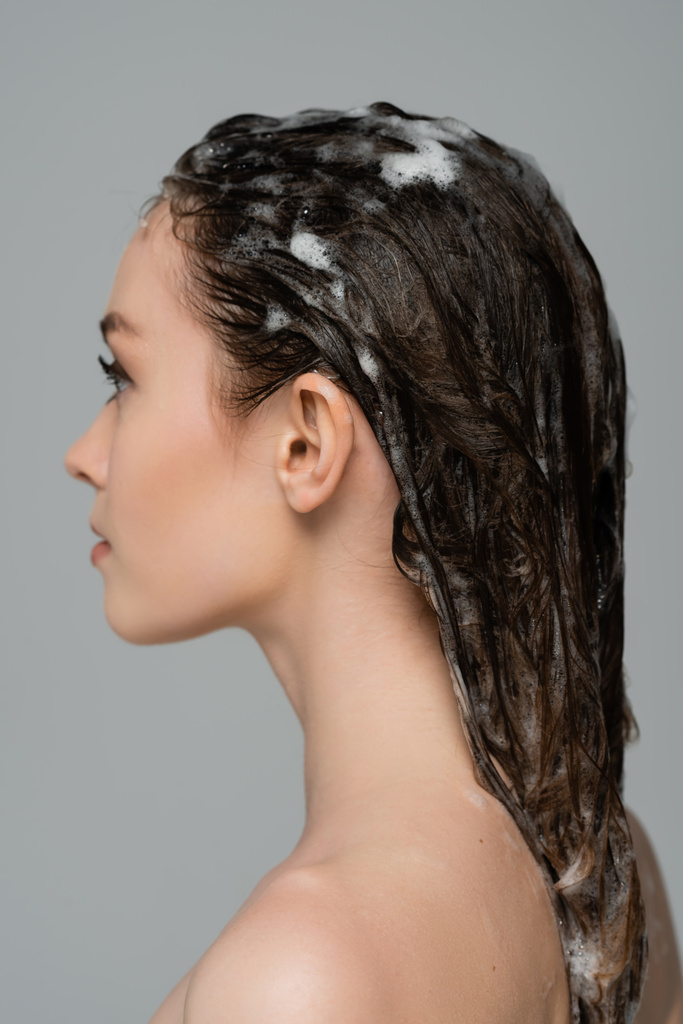 perfil de mujer joven con el pelo espumoso y húmedo aislado en gris - Foto, imagen