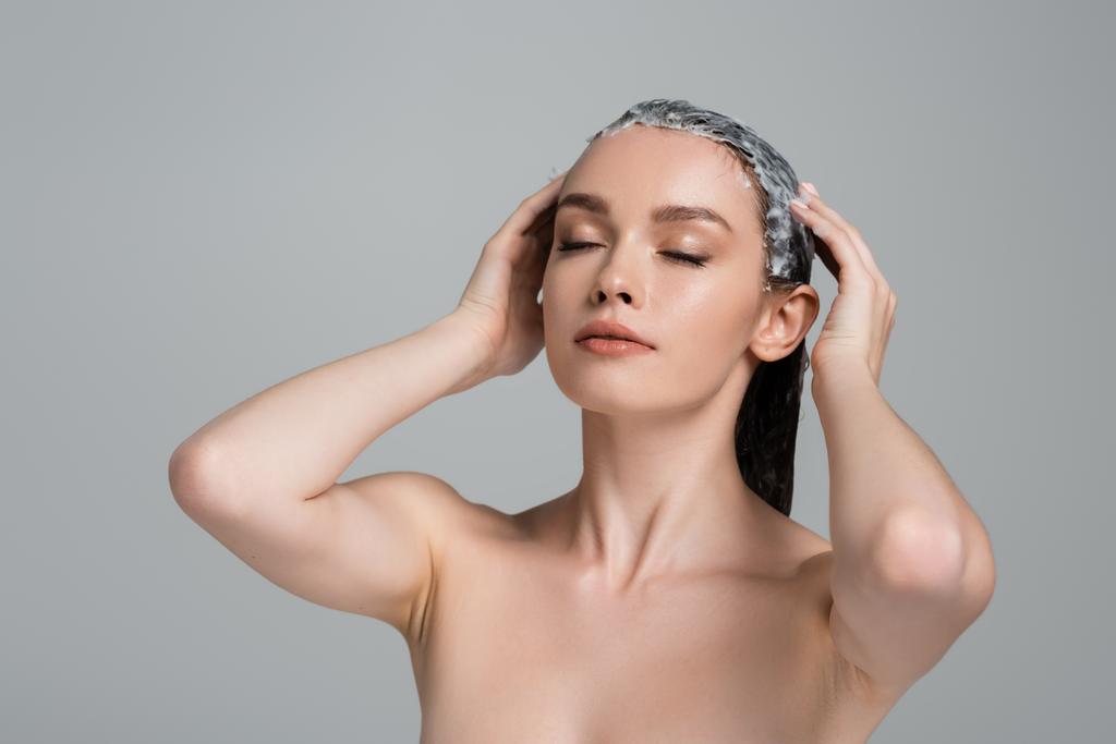 junge Frau mit geschlossenen Augen mit Maske auf nassem Haar isoliert auf grau  - Foto, Bild