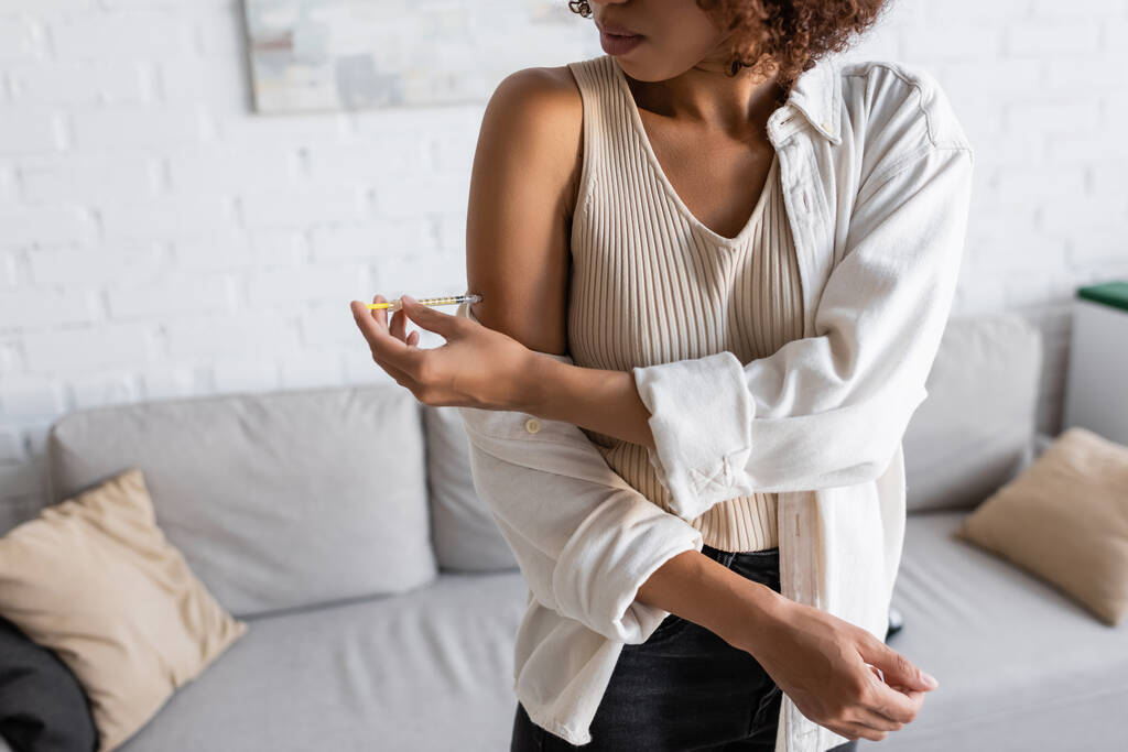 Розбитий погляд на афро - американську жінку, яка впорскує інсулін у руку вдома.  - Фото, зображення