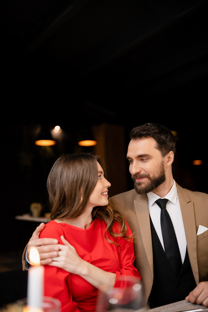 бородатий чоловік обіймає веселу молоду жінку в червоній сукні на день Святого Валентина
  - Фото, зображення