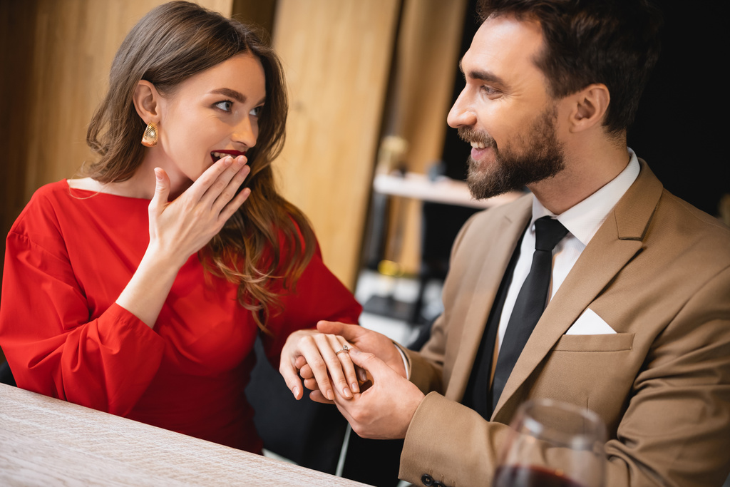 vousatý muž dělat návrh a nosit zásnubní prsten na prst překvapené ženy na Valentýna - Fotografie, Obrázek