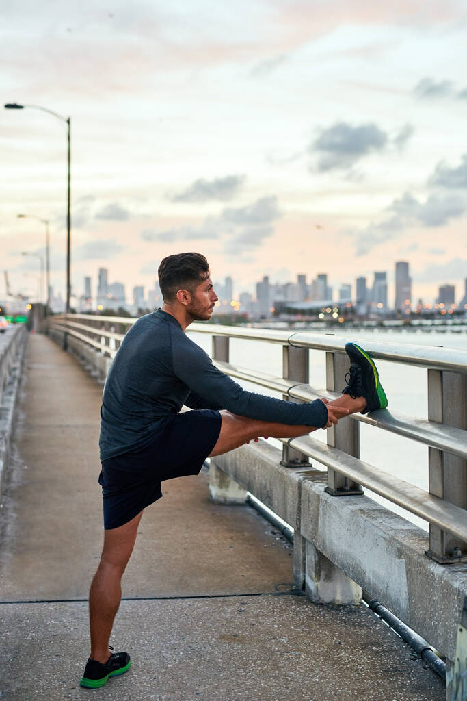 Asegúrese de que cada músculo está listo antes de realizar. un joven guapo haciendo ejercicio al aire libre - Foto, imagen