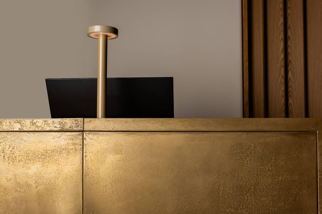 монитор рядом с современной золотой лампой на ресепшене роскошного отеля  - Фото, изображение