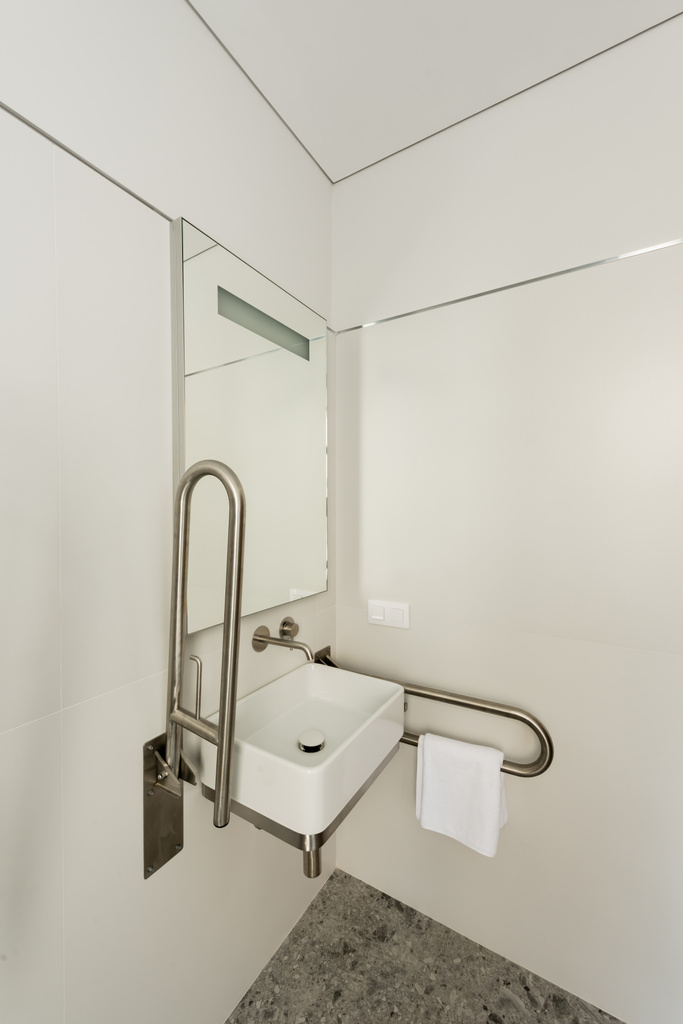 інтер'єр білої ванної кімнати з раковиною і дзеркалом для людей з обмеженими можливостями в готелі
  - Фото, зображення