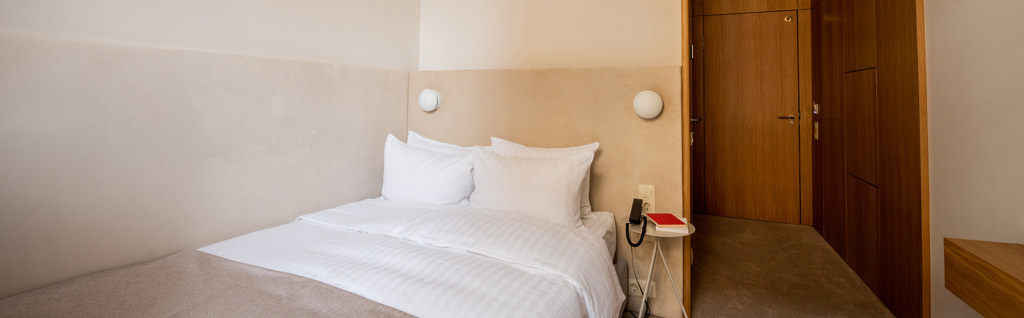 книга и телефон на тумбочке рядом с удобной кроватью с подушками в номере отеля, баннер  - Фото, изображение