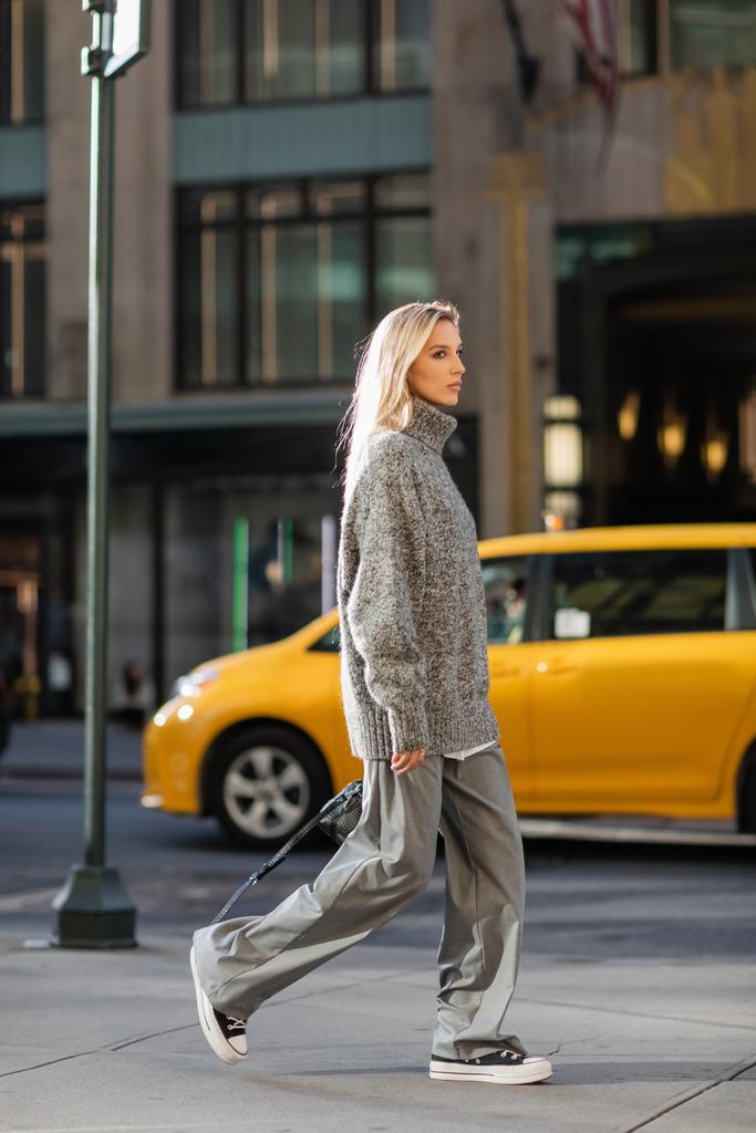 pełna długość stylowa młoda kobieta z blond włosy spaceru w pobliżu żółtej taksówki w Nowym Jorku  - Zdjęcie, obraz