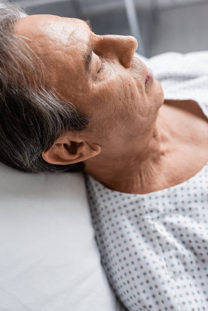 Älterer Patient liegt auf verschwommenem Bett in Krankenhausstation - Foto, Bild
