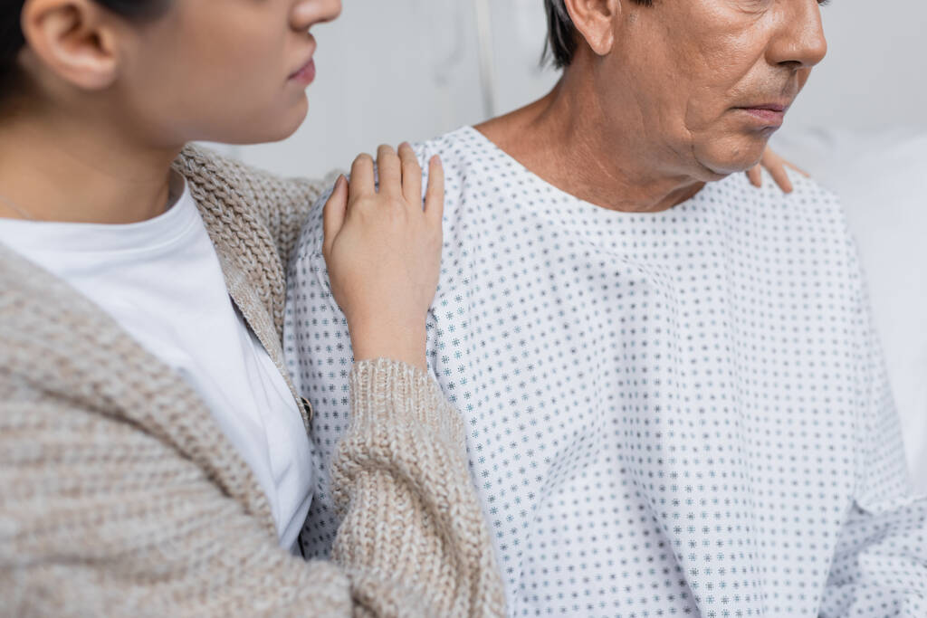 Gewassen beeld van vrouw knuffelen senior vader in patiënt toga in ziekenhuis afdeling  - Foto, afbeelding