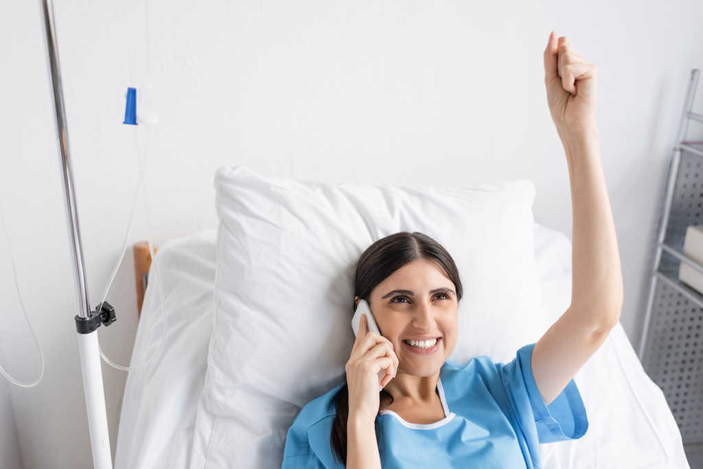 病院のベッドでスマートフォンで話す興奮患者の高い角度ビュー  - 写真・画像