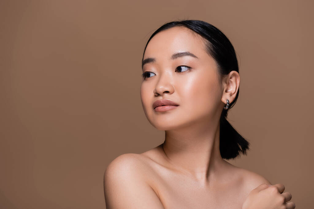 Young asian woman with naked shoulders looking away isolated on brown  - Foto, afbeelding