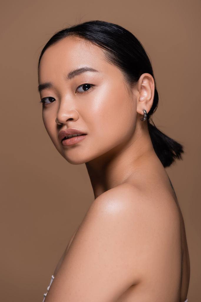 Pretty asian woman with makeup looking at camera isolated on brown  - Fotografie, Obrázek