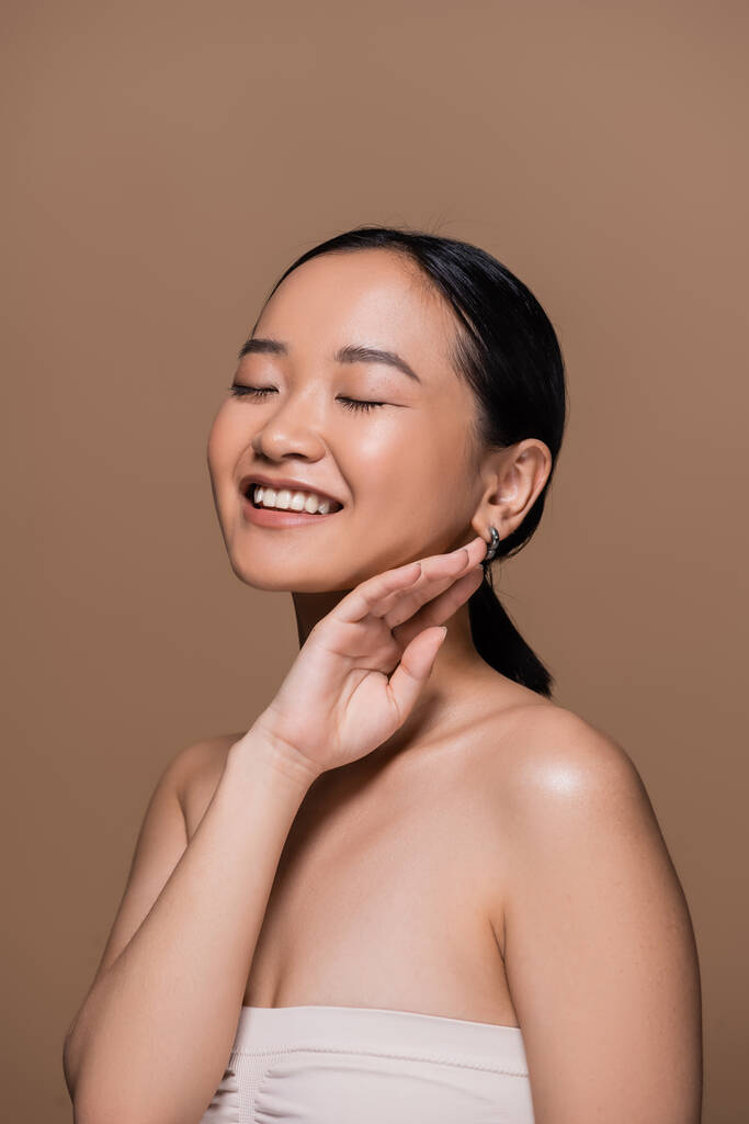 Щаслива азіатська жінка у верхніх закритих очах і зворушливе обличчя ізольовано на коричневому
  - Фото, зображення