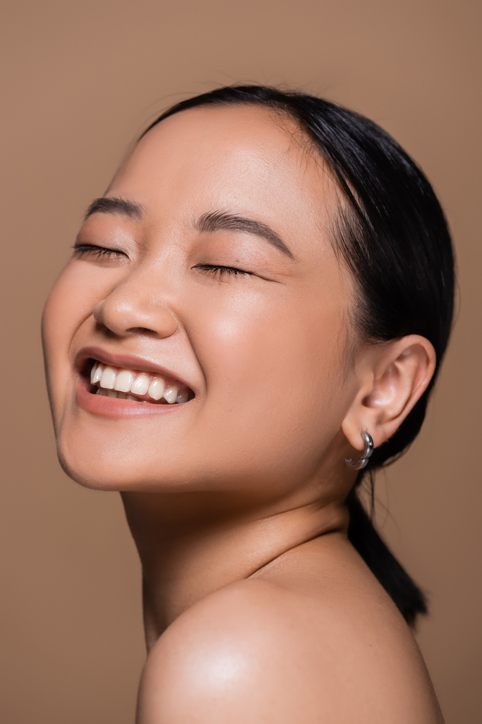 Pretty asian woman with closed eyes posing isolated on brown  - Foto, immagini
