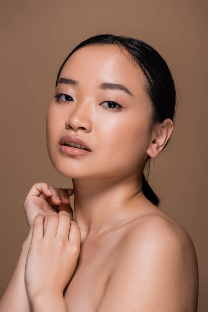 Portrait of brunette asian model looking at camera isolated on brown  - Fotoğraf, Görsel