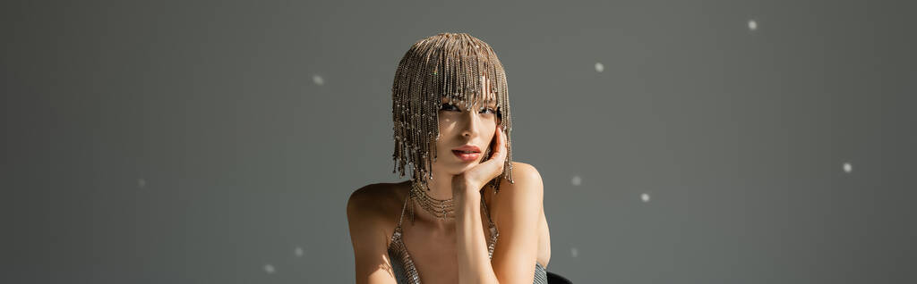 young model with metallic headwear with jewelry looking at camera on grey, banner - Photo, Image