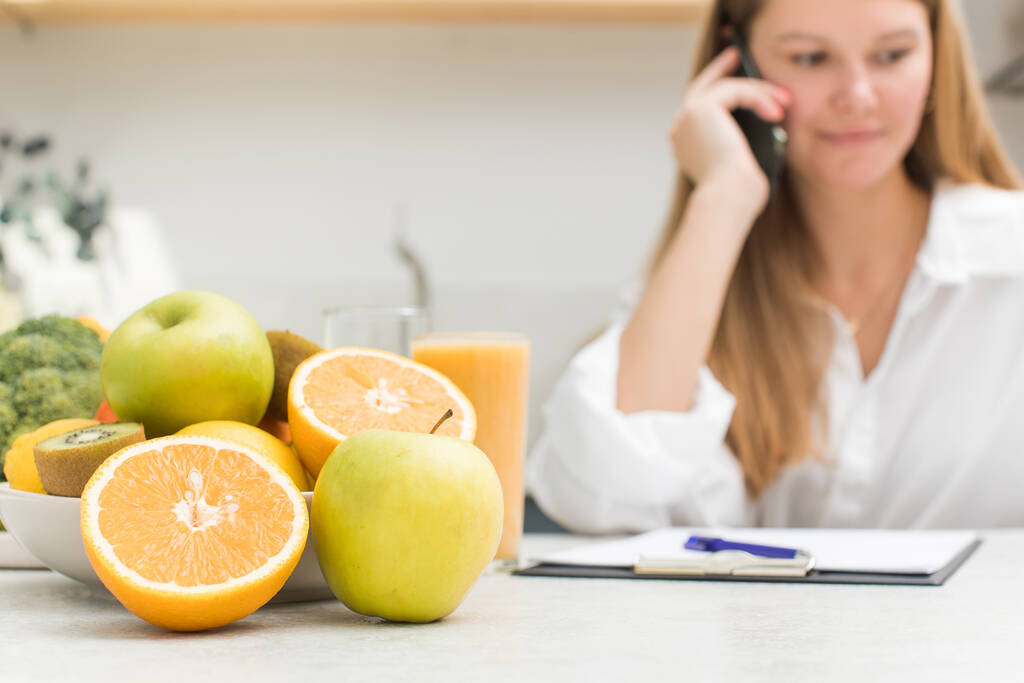 Een voedingsdeskundige adviseert een klant telefonisch, verse groenten en fruit liggen op tafel. Selectieve focus. - Foto, afbeelding
