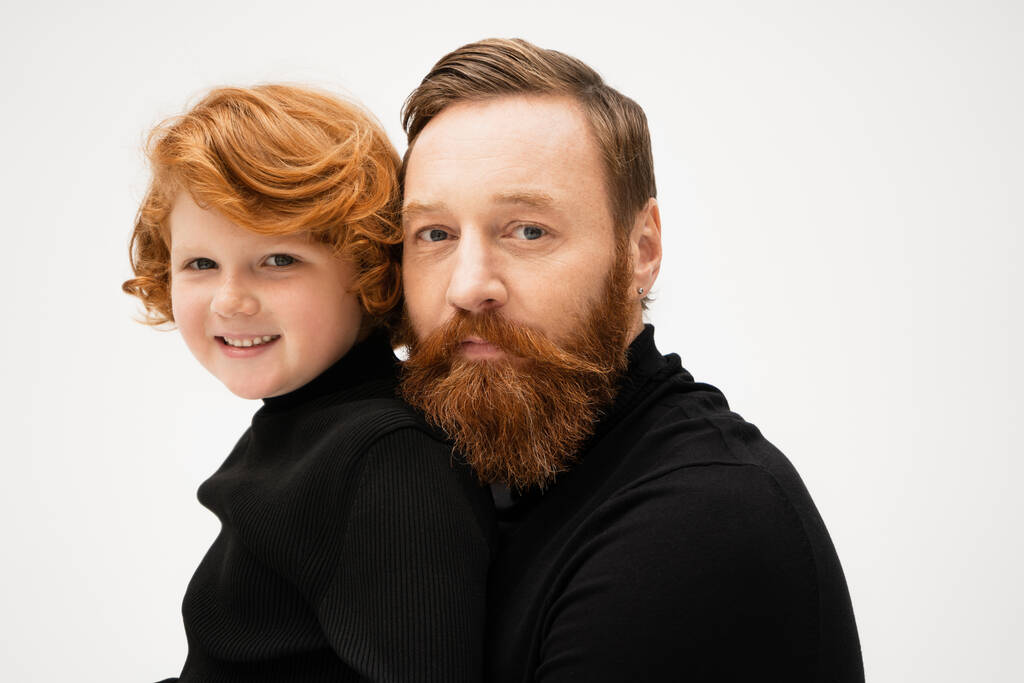 family portrait of bearded man with smiling red haired grandson in black turtlenecks smiling at camera isolated on grey - Foto, immagini