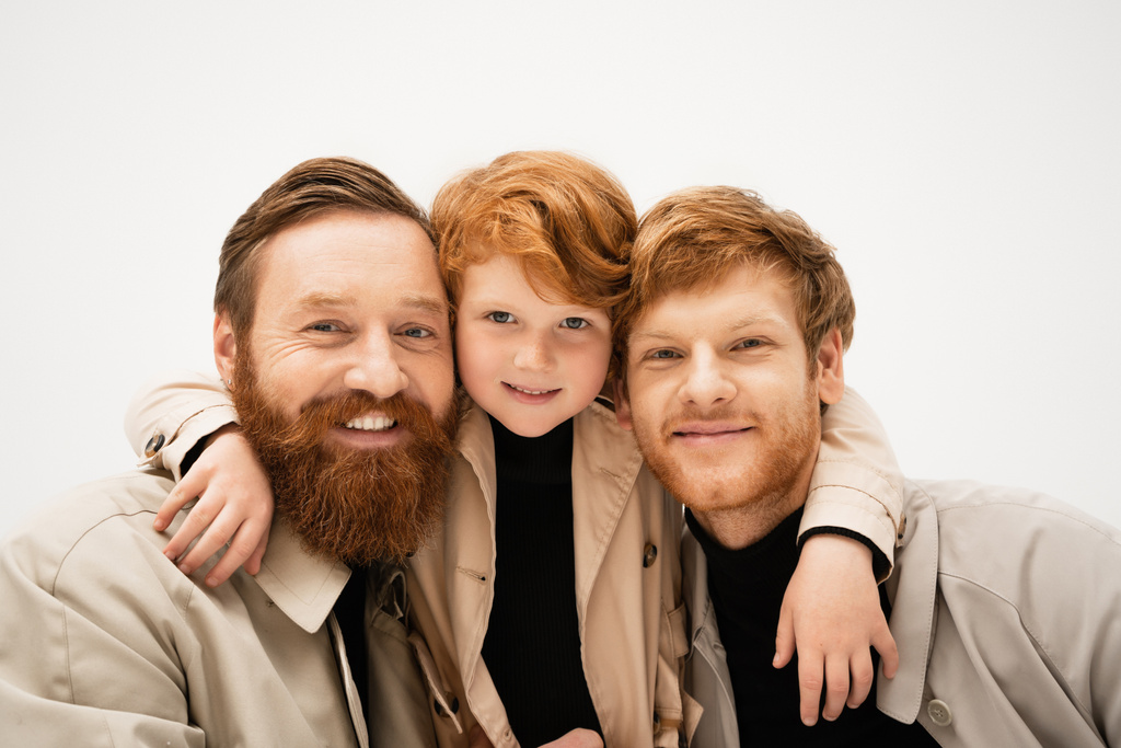 family portrait of red haired boy hugging cheerful bearded grandfather and dad isolated on grey - Foto, immagini