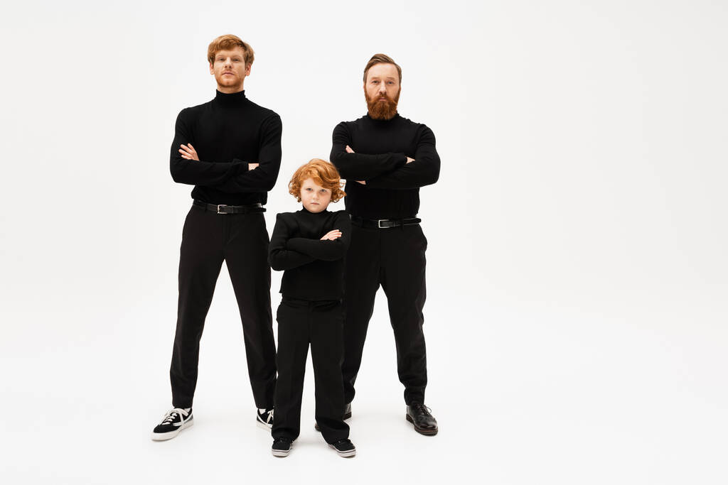 full length of redhead men and boy in black clothes posing with crossed arms on light grey background - Foto, imagen
