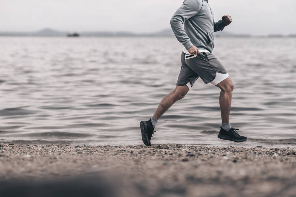 zdravý životní styl mladý fitness muž běží na přímořské pláži. Venkovní cvičení, Zdravý životní styl koncept. - Fotografie, Obrázek