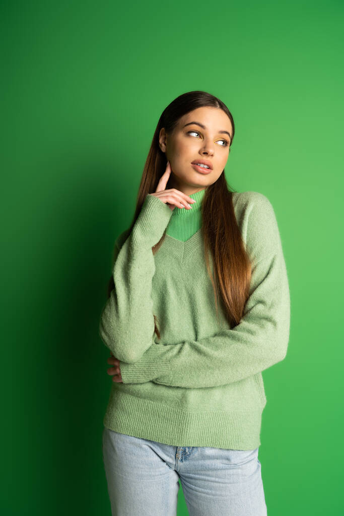 Brunette teen girl in jumper looking away on green background  - Valokuva, kuva